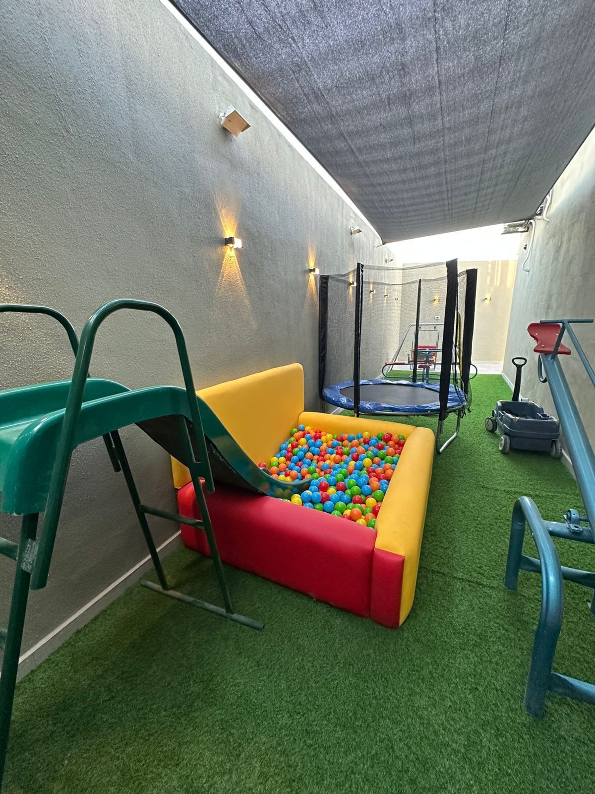 Zona de juegos con piscina de pelotas, tobogán y trampolín.