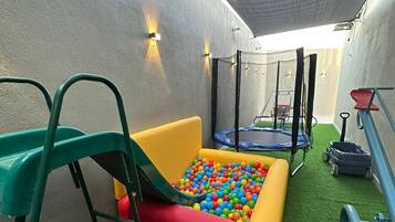Zona de juegos con piscina de pelotas, tobogán y trampolín.