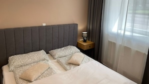 Ein ordentlich bezogenes Bett mit Kissen und einem Nachttisch mit einer Lampe.