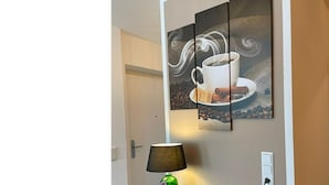 Eine Wand mit einem Kaffee-Motiv, einer Lampe und einer Tür.