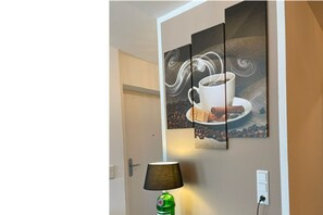 Eine Wand mit einem Kaffee-Motiv, einer Lampe und einer Tür.