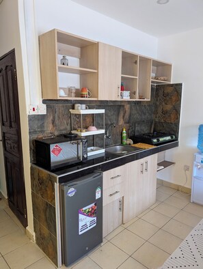 Eine Küche mit Kühlschrank, Mikrowelle, Spüle und Holzschränken.