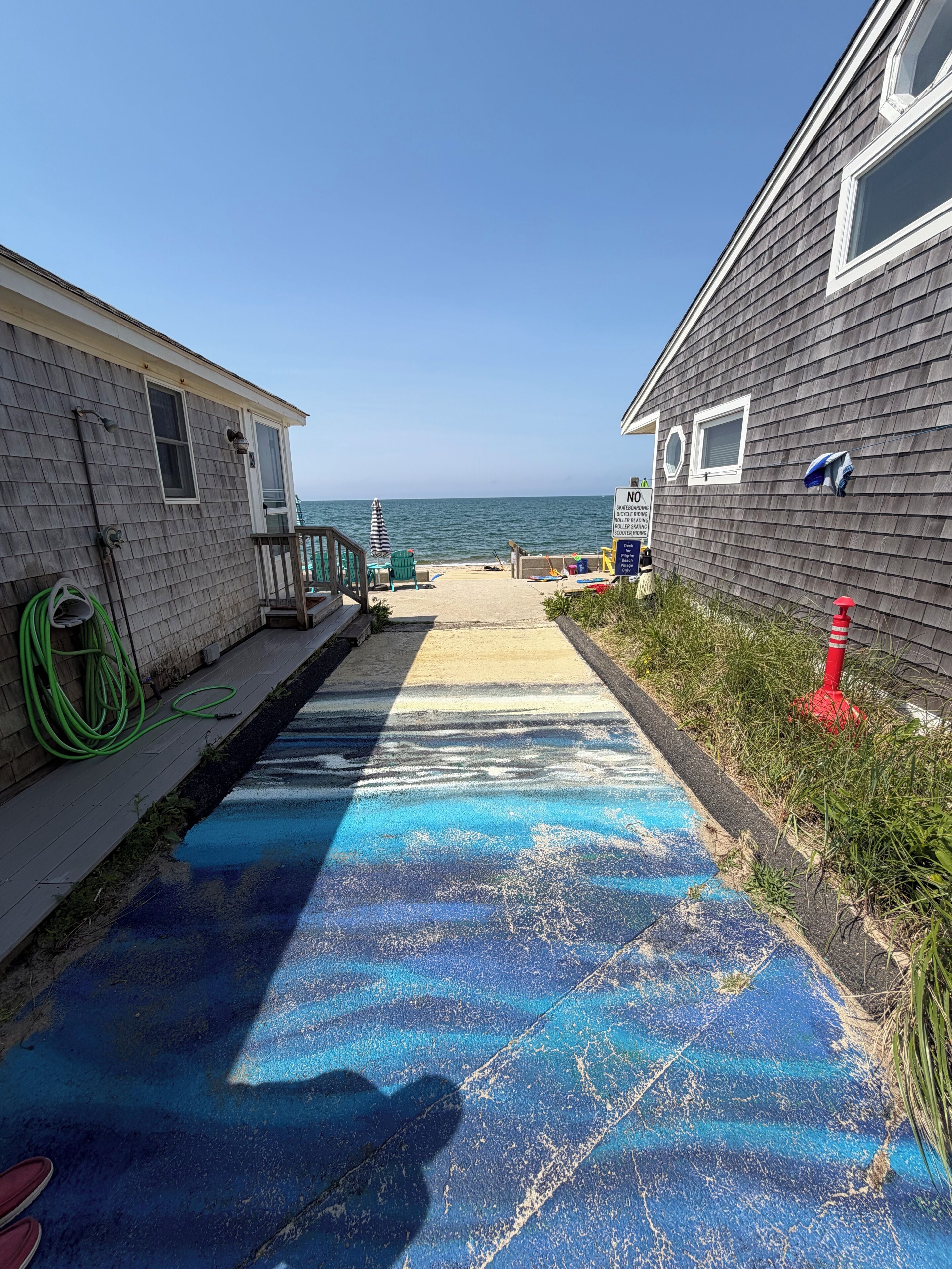 Ein Weg, der zu einem Strand führt, mit einem Haus links und einer Garage rechts.
