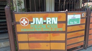 Una entrada con portón y un cartel que indica 'JM-RN Pensione House', mostrando que es un hogar para personas mayores.