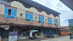 Um edifício com várias lojas, um letreiro para um bar-café no píer, e uma motocicleta estacionada.
