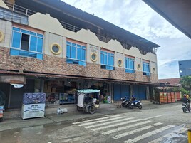 Un edificio con varias tiendas, un letrero para un bar cafetería en el muelle, y una motocicleta estacionada.