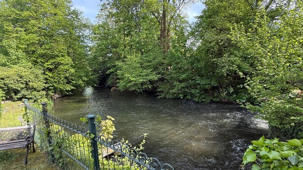 Une rivière bordée d’une clôture en métal et d’un banc.