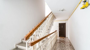 A staircase with white railings and wooden handrails, leading to a dark door.