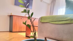 A living room with a sofa, a coffee table with a plant, a wooden cabinet, and a wall-mounted TV.