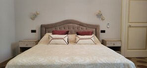 A bedroom with a large bed, two nightstands, a wall-mounted light fixture, and a door. - Adorable little villa in the center of Santa Maria di Leuca (Santa Maria di Leuca)