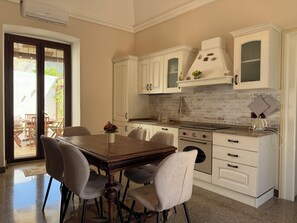 A kitchen with white cabinets, a wooden dining table, and chairs. - Adorable little villa in the center of Santa Maria di Leuca (Santa Maria di Leuca)