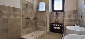 A bathroom with a glass-enclosed shower, a white sink, and a shelf with towels. - Adorable little villa in the center of Santa Maria di Leuca (Santa Maria di Leuca)