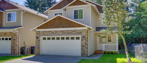 A two-story residential building with a garage, a front porch, and a well-maintained lawn.
