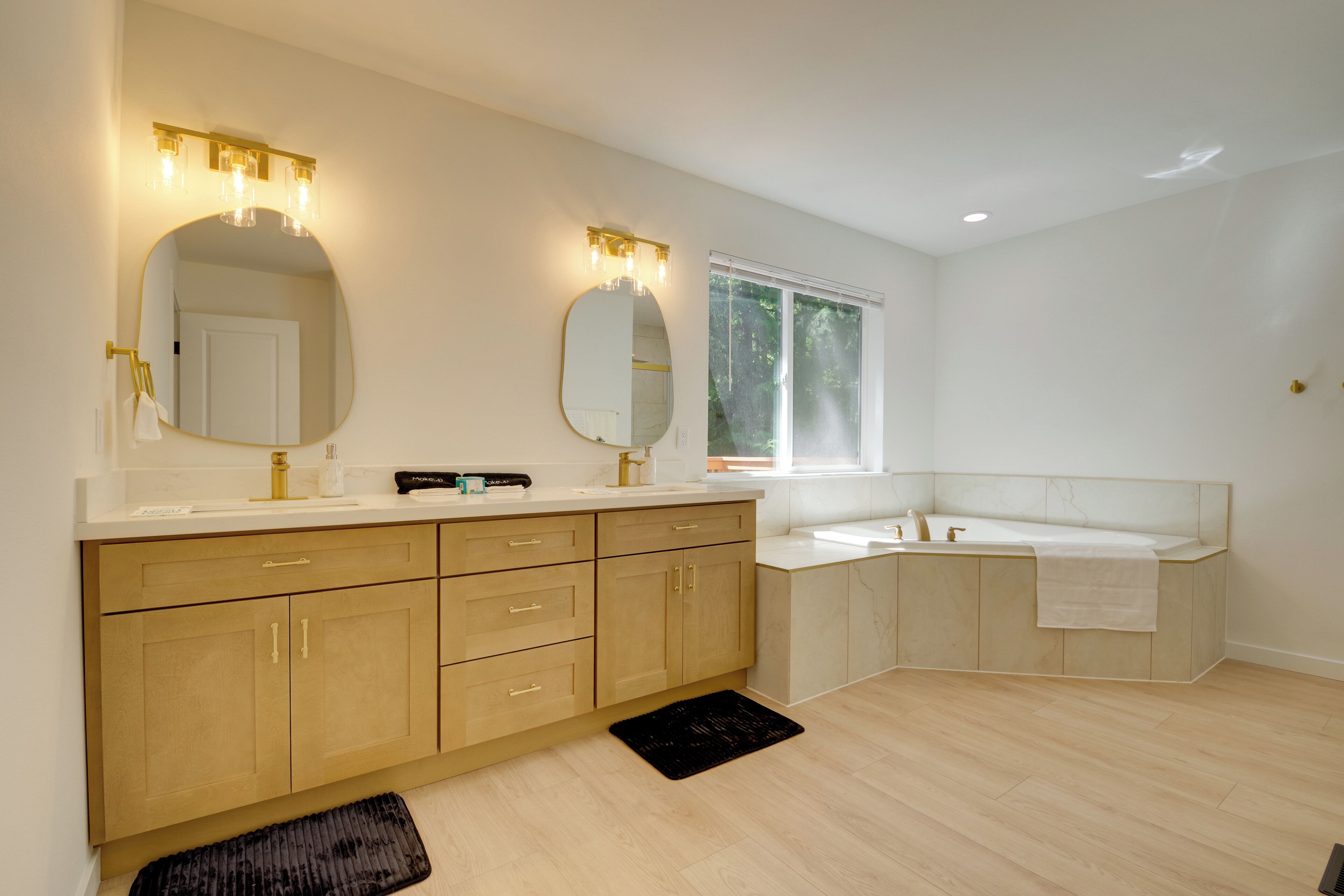 A modern bathroom with two sinks, a large mirror, and a bathtub.