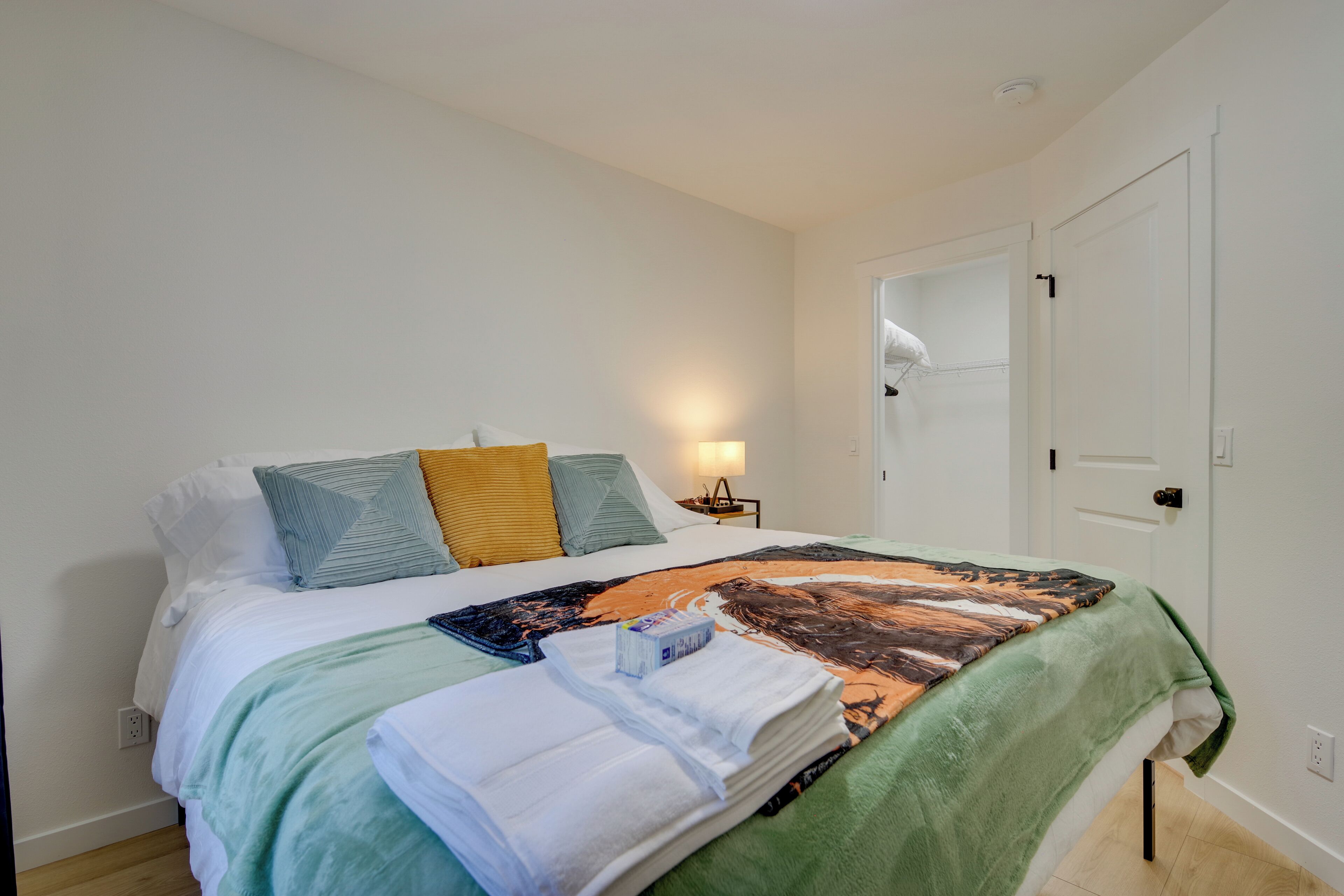 Un lit bien fait, avec une couvre-lit à motifs, des oreillers et des serviettes pliées.