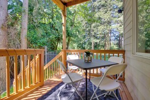 Una terraza de madera con una mesa y sillas, rodeada de árboles.