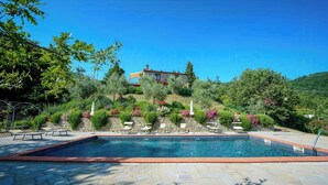 A swimming pool with stone tiles, surrounded by greenery and a hillside view. - Umbrian Hillside House with Stunning Views (Lisciano Niccone)