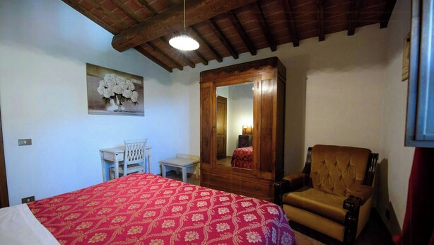 A bedroom with a bed, a wooden chair, a desk, and a mirror. - Umbrian Hillside House with Stunning Views (Lisciano Niccone)