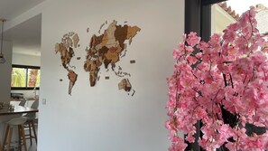 A world map mural on a wall, a kitchen area with a dining table and chairs, and a potted plant with pink flowers. - Family villa with pool and palm trees, between sea and garrigue (Teyran)