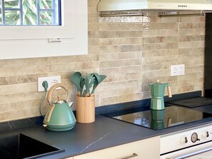 A kitchen with a stove, a kettle, and a utensil holder on the counter. - New Valparaiso house with private pool 8 people (Cunit)