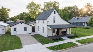 A two-story house with a covered porch, a front yard, and a driveway.