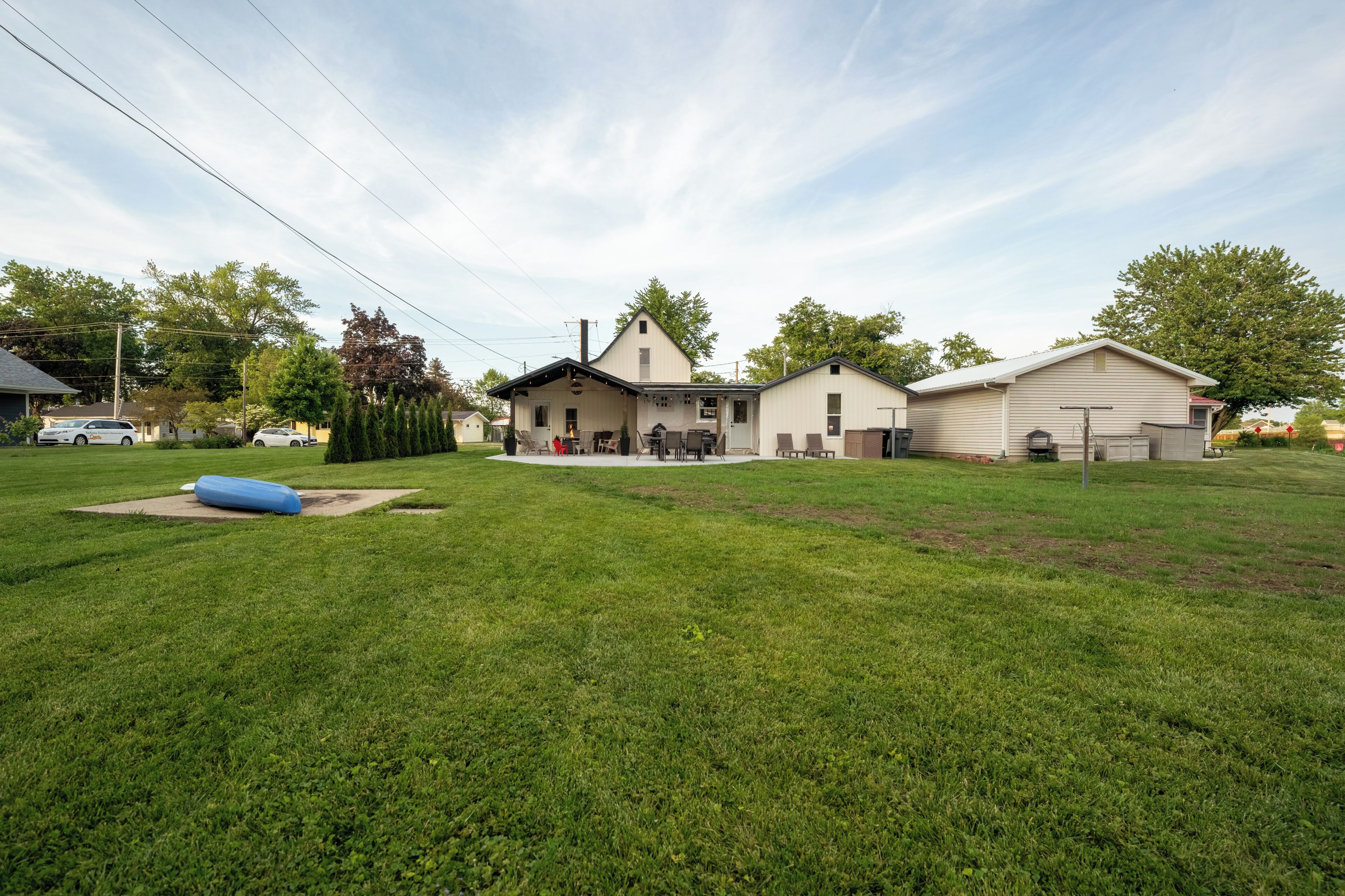 A residential area with a large lawn, a house with a garage, and a small shed.