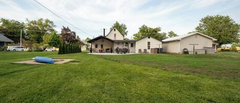 A residential area with a large lawn, a house with a garage, and a small shed.