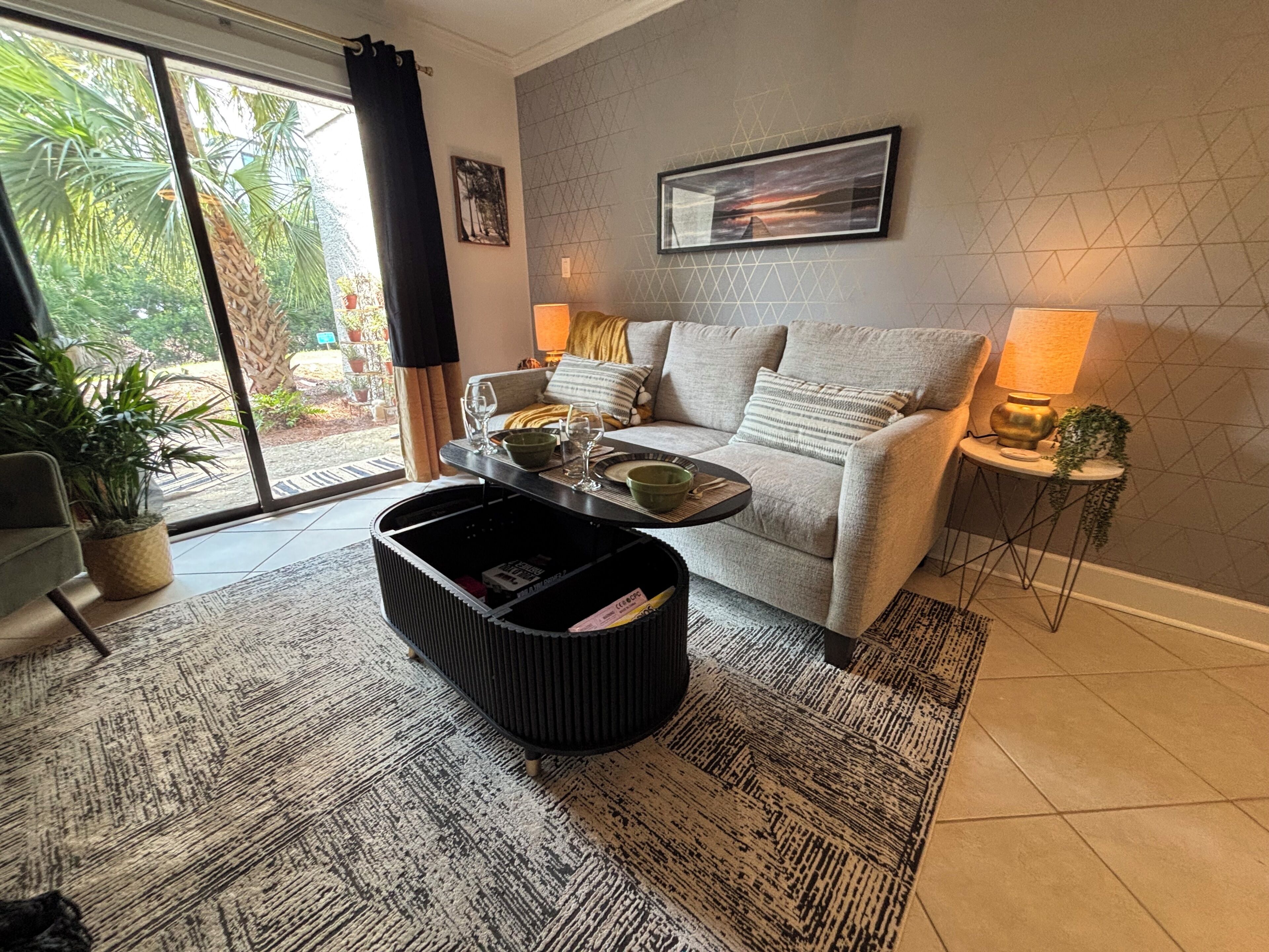 A modern living room with a sofa, coffee table, and a large window with curtains.
