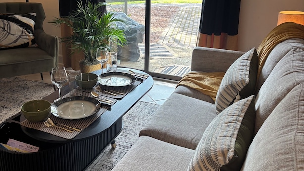 Ein Wohnzimmer mit einer Couch, einem Couchtisch und einem Esstisch für zwei Personen.