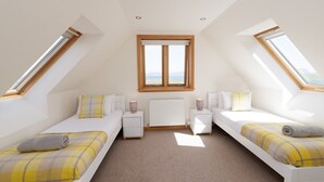 A bedroom with two beds, a window, a radiator, and skylights.
