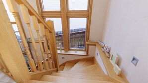 A wooden staircase with a view of a balcony outside.