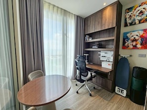 A hotel room with a wooden desk, a chair, a round table, a bookshelf, and a painting on the wall. - Luxury 1BR Plus at Veha Hua Hin | Panoramic Sea View & Near Beach (Tambon Nong Kae)