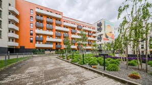 A multi-story building with balconies, a paved courtyard, and landscaped areas with shrubs and trees. - Wrocław Gaj Studio - Balcony - by Rentujemy (Wrocław)