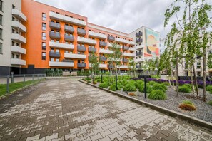 A multi-story building with balconies, a paved courtyard, and landscaped areas with shrubs and trees. - Wrocław Gaj Studio - Balcony - by Rentujemy (Wrocław)