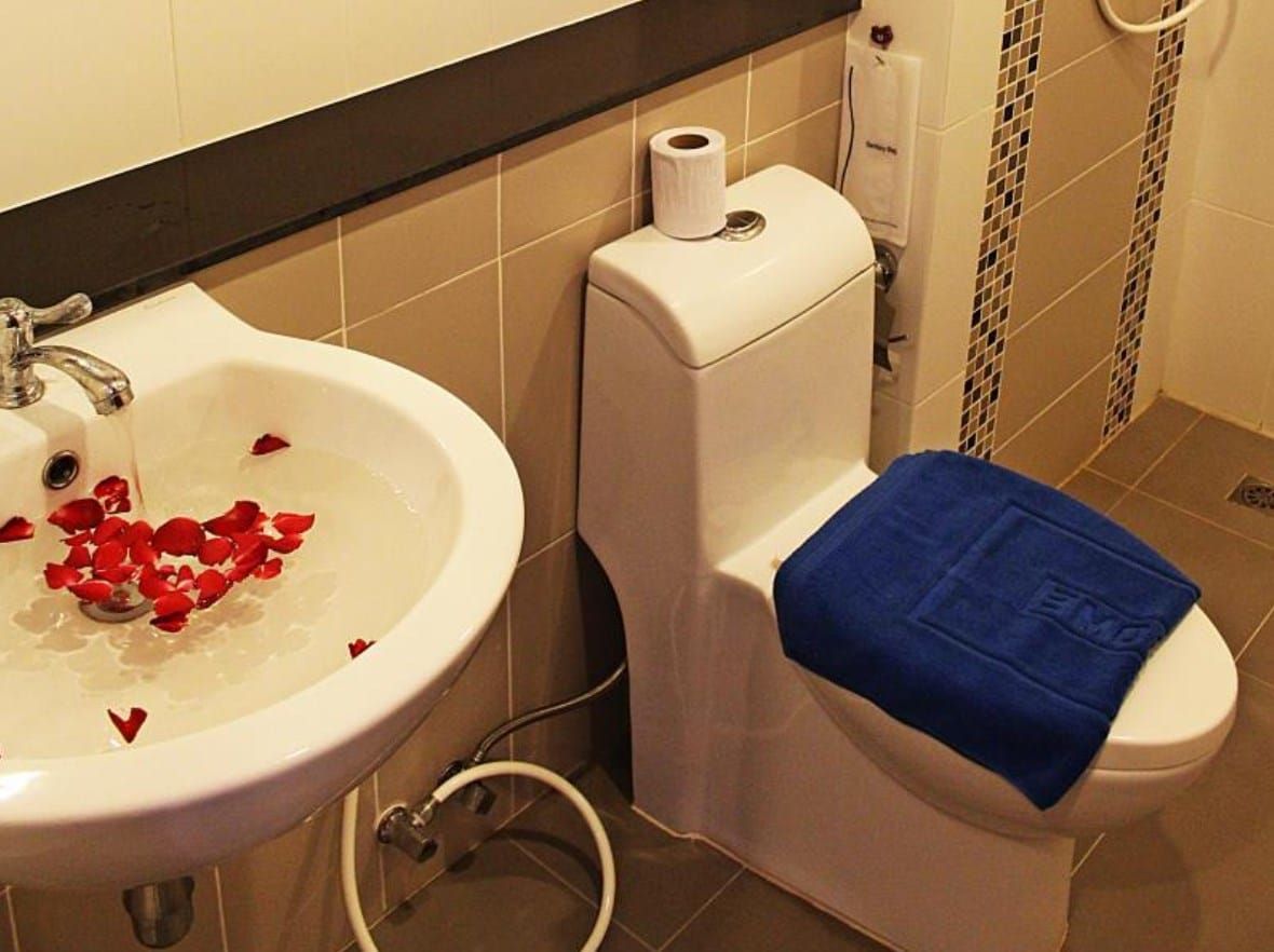 A bathroom with a white sink, toilet, and a blue towel on the toilet.