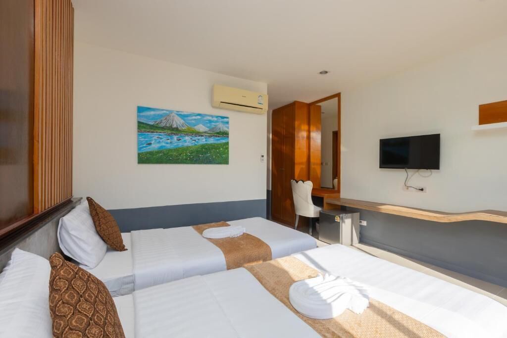 A hotel room with two beds, a desk, a chair, a TV, and a painting on the wall.