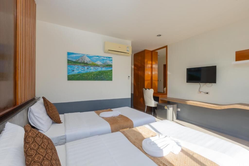 Habitación de hotel con dos camas, un cuadro, un televisor y un equipo de aire acondicionado.