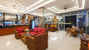 Eine moderne Hotelhalle mit Korbmöbeln, einer Bar und großen Fenstern.