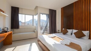 Ein Hotelzimmer mit Bett, Sofa, Schreibtisch und Blick auf die Stadt.