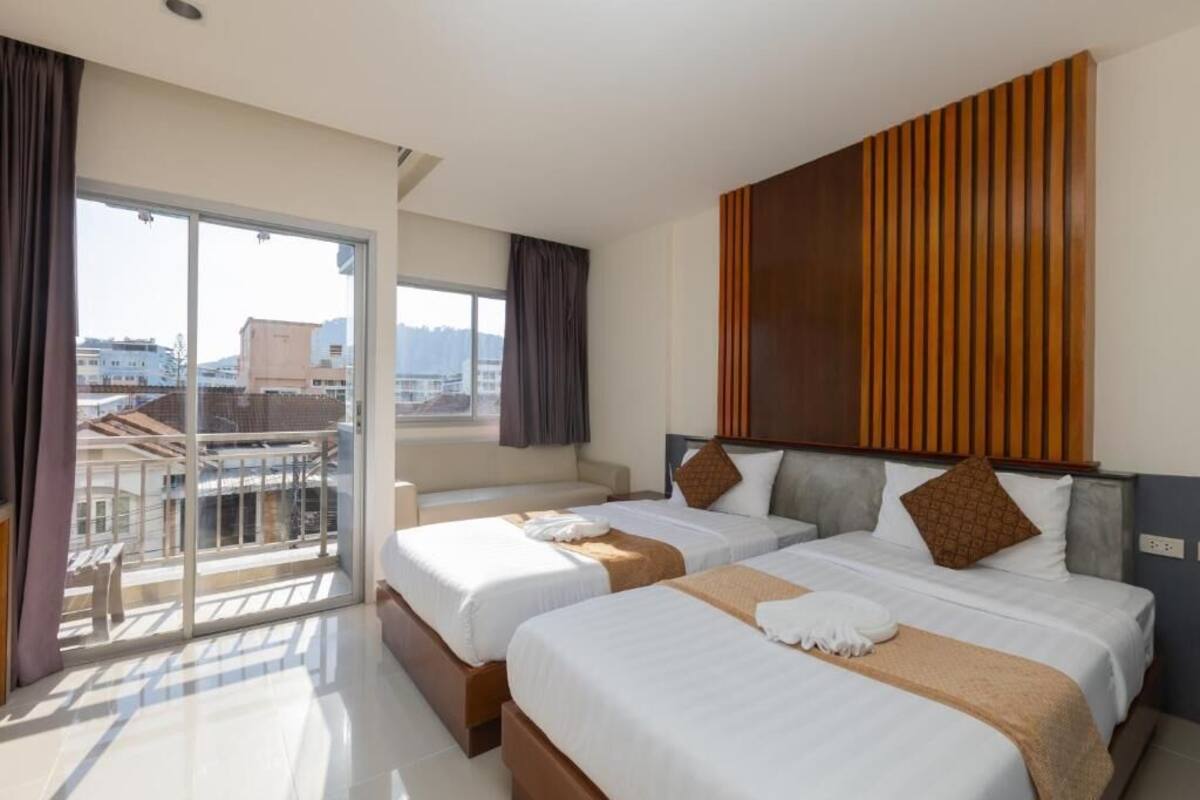 A hotel room with two beds, a balcony, and a city view.