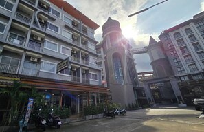 A multi-story building with balconies, a tower, and a sign for a guesthouse. - Baan Ketkaew Patong (Patong)