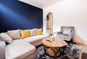 Ein modernes Wohnzimmer mit einer Couch, einem Sessel und einem runden Couchtisch.