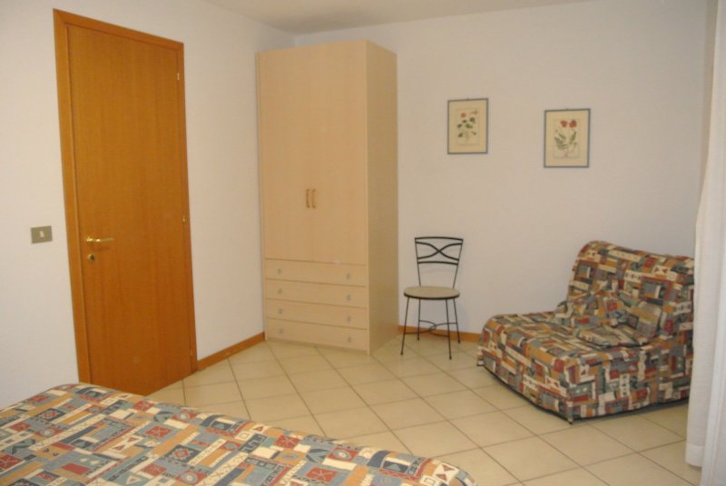 Ein Schlafzimmer mit einem Bett, einem Kleiderschrank, einem Sessel und einem Sofa.