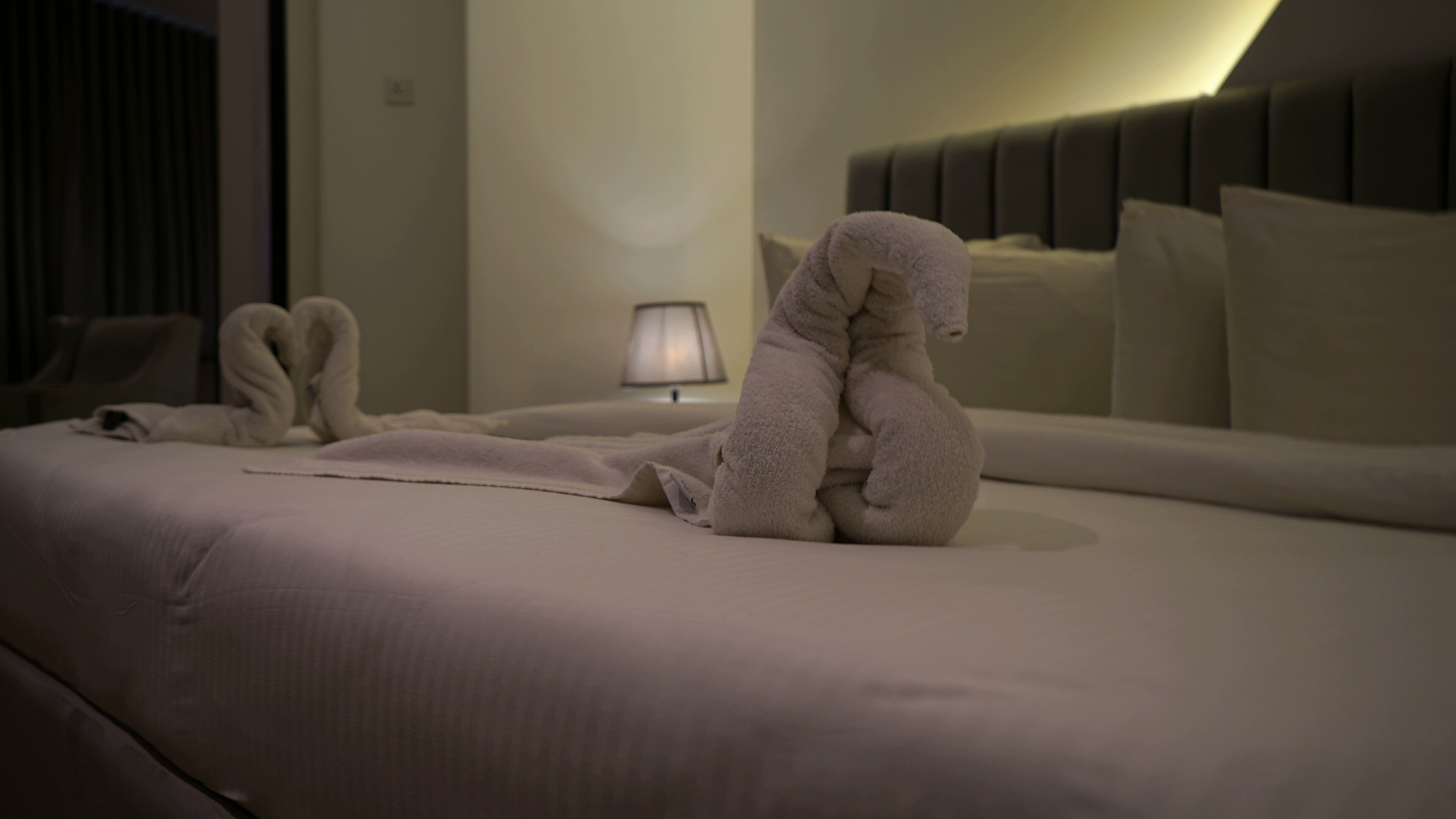 Ett hotellrum med en säng, kuddar, en lampa och en sänggavel.