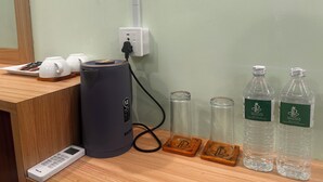Una barra de madera con una cafetera, un control remoto y dos botellas de vidrio con etiqueta.