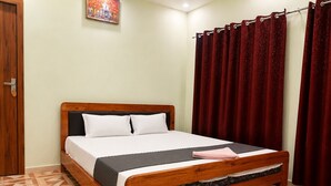 Una cama de madera con cabecera, almohadas blancas y una manta gris.
