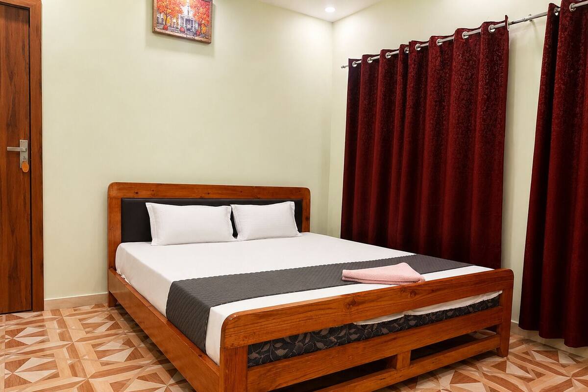 Una cama de madera con cabecera, almohadas blancas y una manta gris.