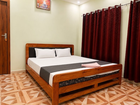 A wooden bed with a headboard, white pillows, and a gray blanket.