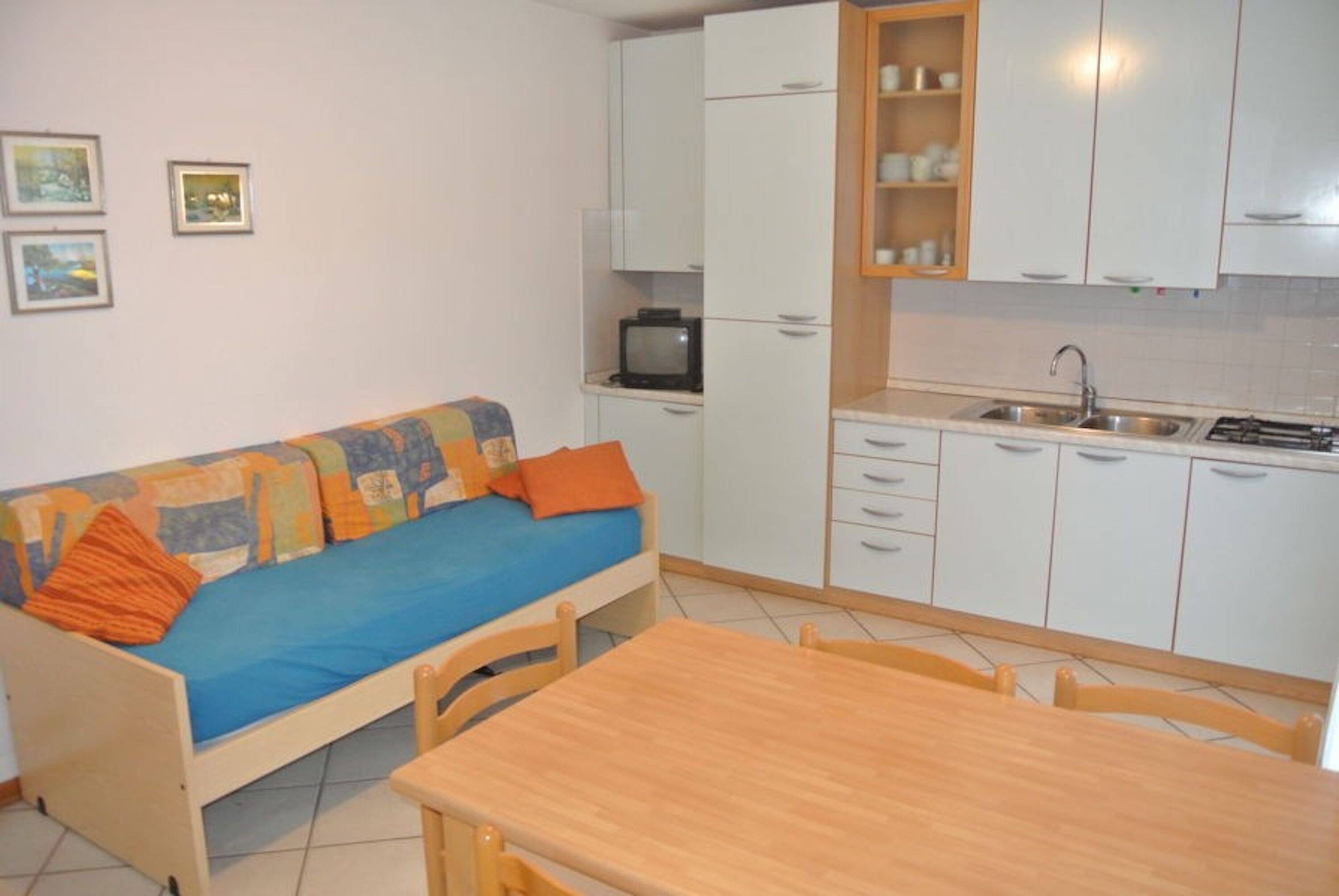 A compact living space with a sofa, a small table, and a kitchenette.