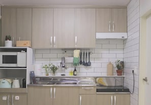 A kitchen with light wood cabinets, a stainless steel sink, and a microwave. - Experience Seoul in a quiet area, just 4 minutes from Dapsimni Station. (Seoul)